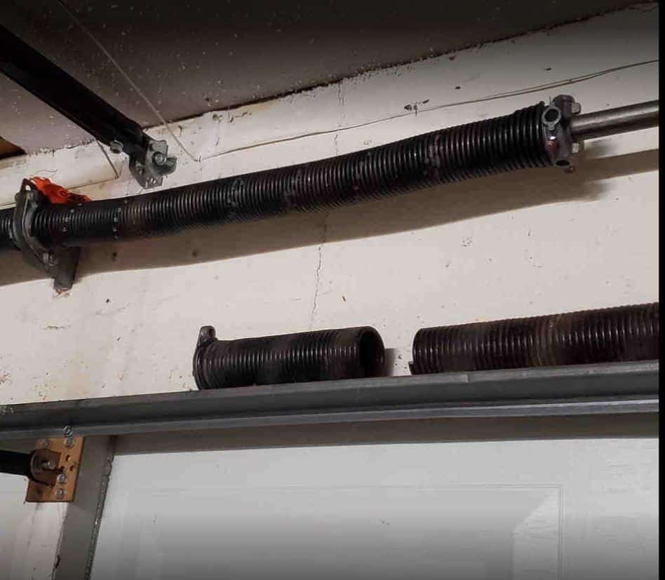 a professional technician fixing a garage door spring, showcasing the tools and components involved in the repair process. The scene highlights the expertise required for safe and effective spring replacement, emphasizing the service quality provided by Garage Door Repair Services Cloud FL.