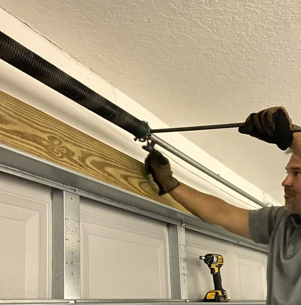 a technician performing garage door spring repair, highlighting the tools used and the precision required for effective service. Caption emphasizes the expertise of Garage Door Repair Services Cloud FL in handling various spring repair needs, ensuring safety and functionality.